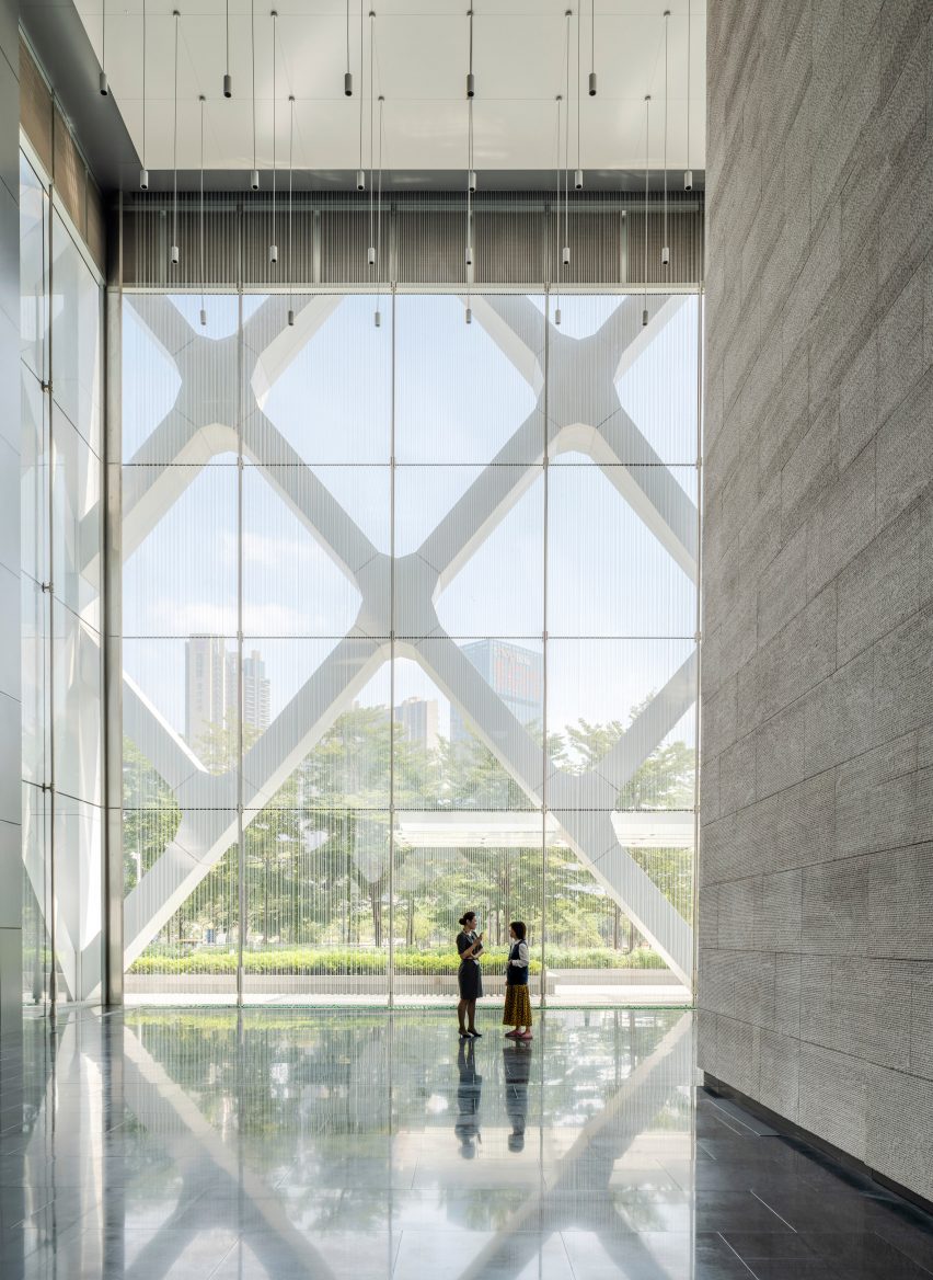 Lobby of SOM's Shenzhen bank building with stone-clad walls on one side and rain-curtain feature in the foreground and exterior diagrid structure visible behind it