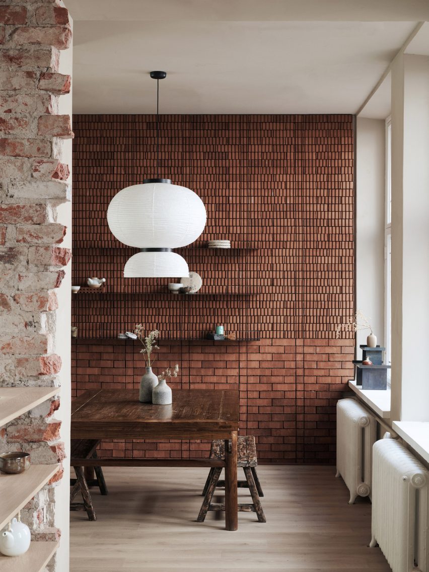 Tea tasting room with red brick wall and paper lantern above weathered wooden table in Teemaa teahouse in Helsinki, designed by Yatofu