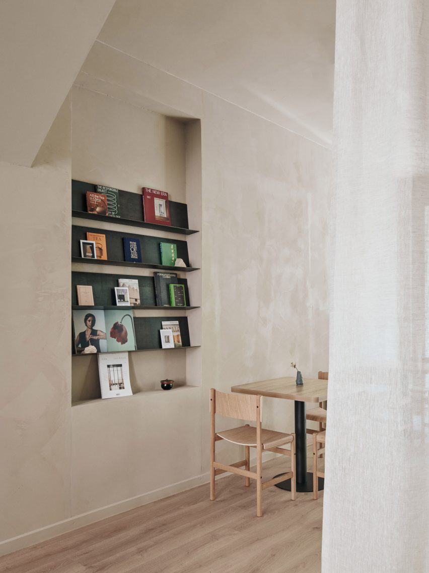 گوشه دیواری با مجلات نمایش داده شده در قفسه‌های کنار میز بلوط در Teemaa Helsinki