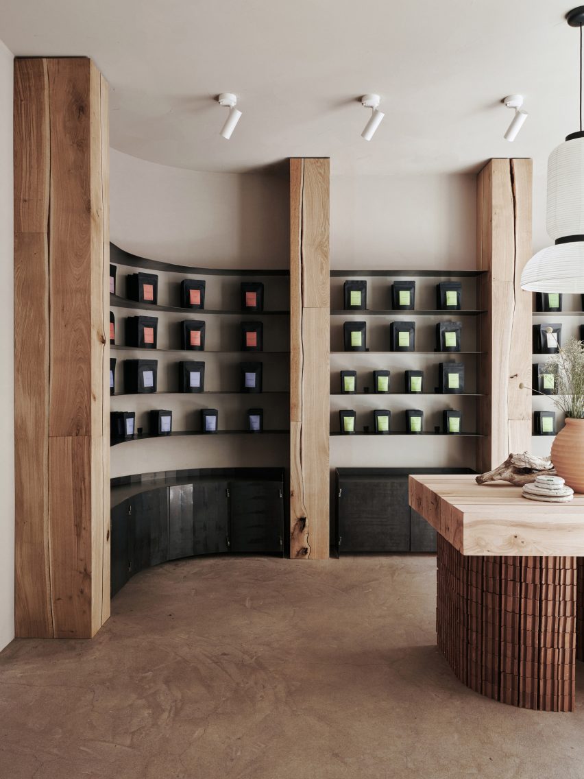 چای در کیسه های مشکی روی دیوار قفسه های منحنی ساخته شده از بلوط و فولاد اکسید شده در Teemaa Helsinki نمایش داده شده است.