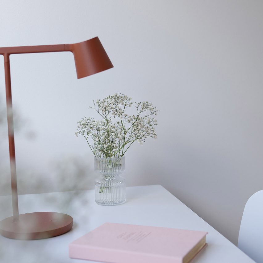 Teknos paint in a cool-toned mauve colour used on a wall with a white desk, red desk lamp, pink diary and a glass jar of flowers