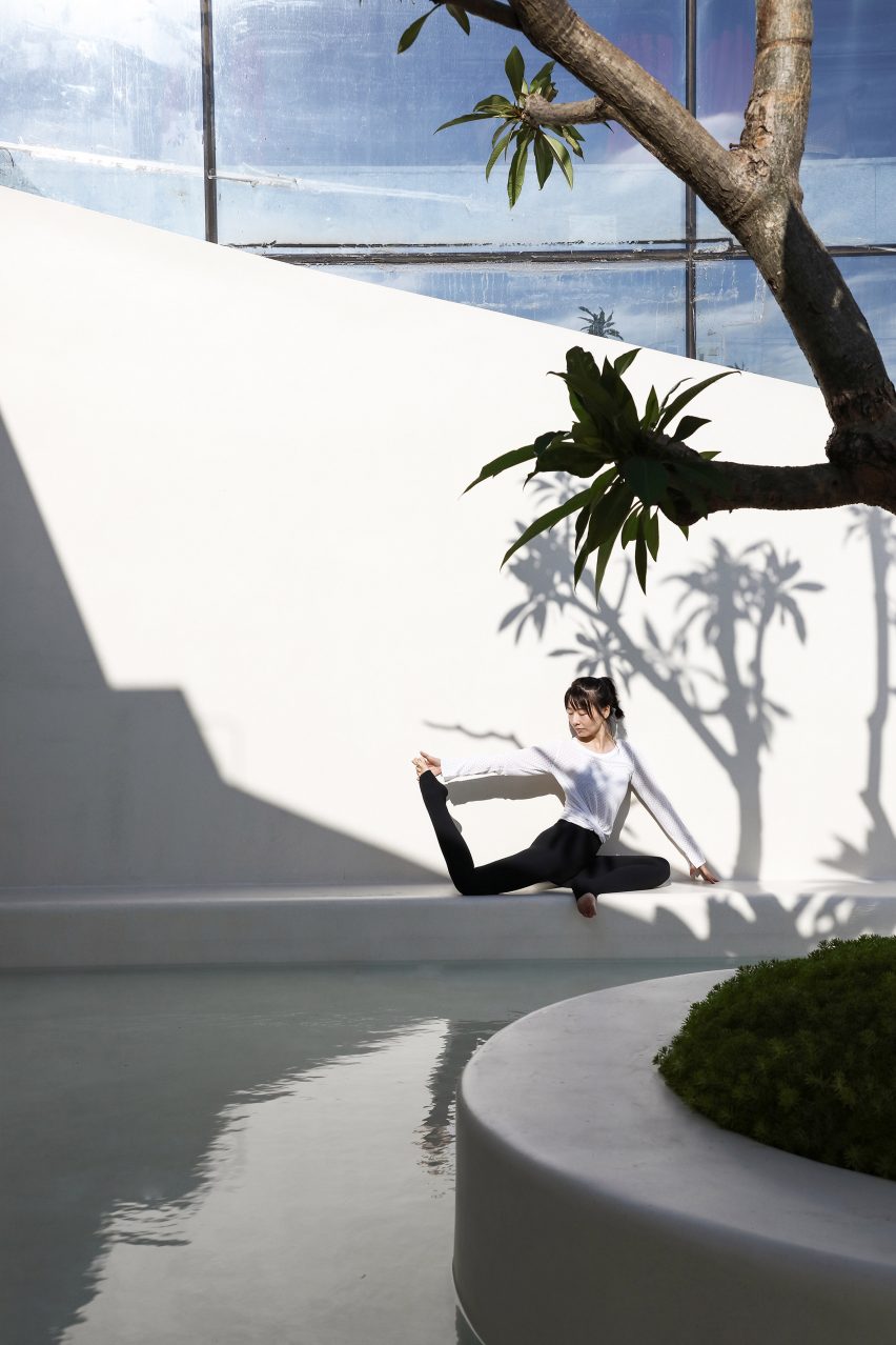 Woman doing yoga next to a shallow pool surrounding a tree in the courtyard of T.T. Pilates