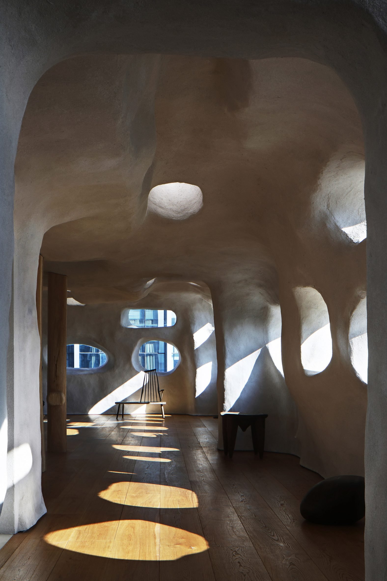 T.T. Pilates studio with rock-like walls and ceilings and rounded openings funnelling light onto a wooden floor