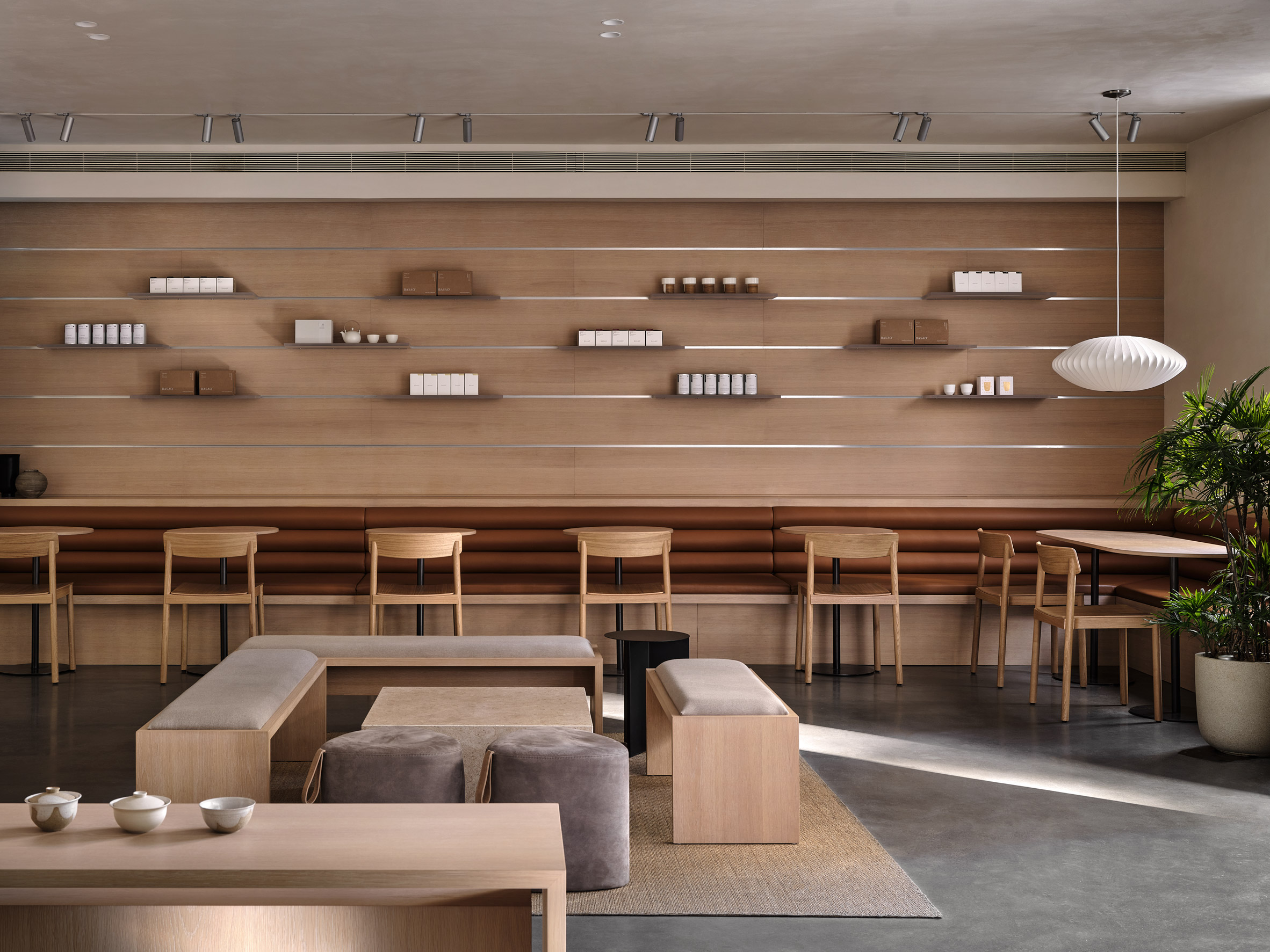 Leather-upholstered banquette next to suede covered benches and poufs in Xiamen teahouse designed by Norm Architects