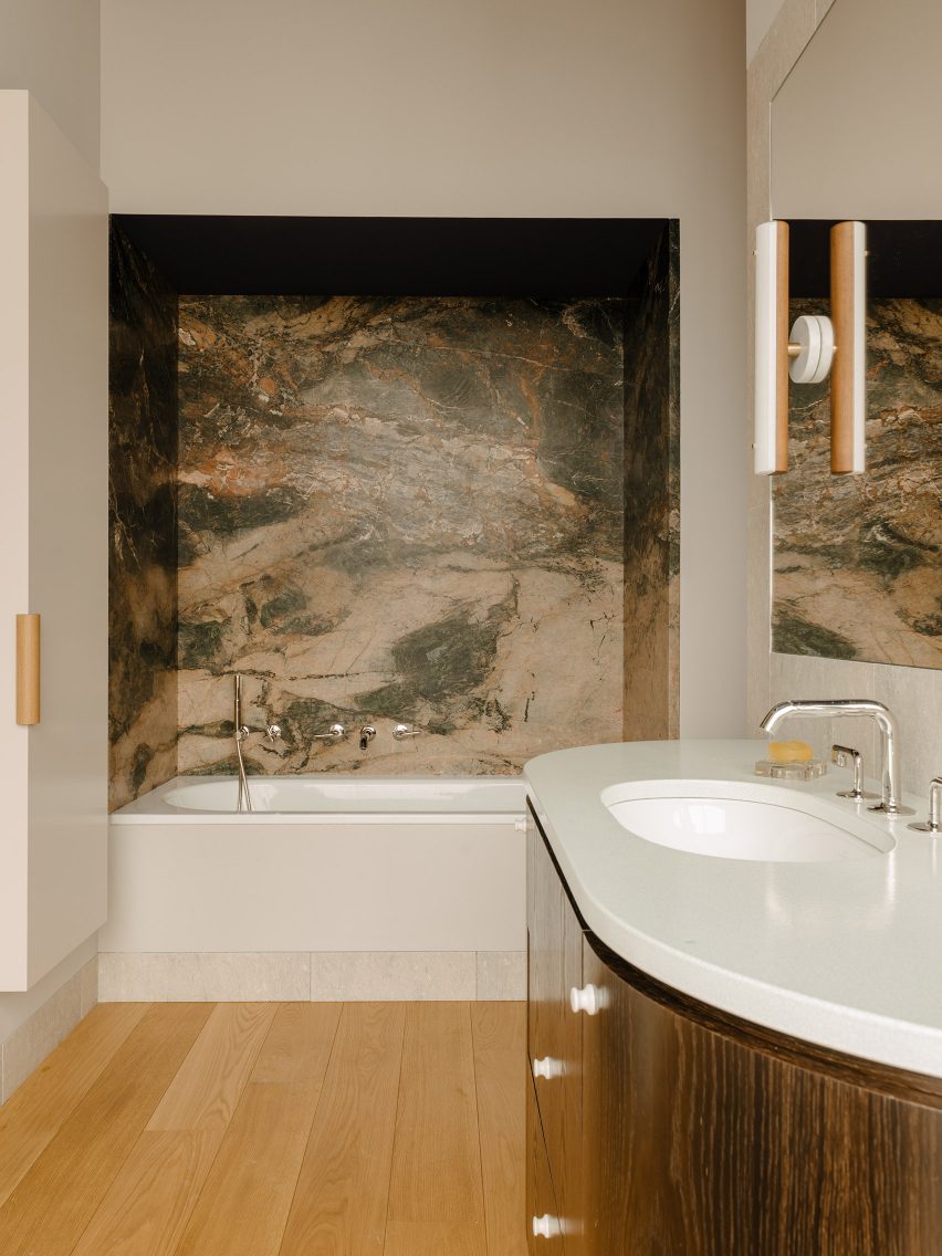 Guest bathroom inside Berlin apartment designed by Gisbert Poppler with marble-clad bath nook and lava stone counter