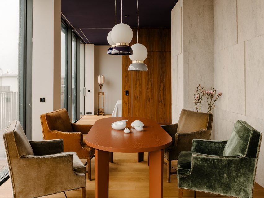 Bespoke wooden dining table surrounded by four armchairs and illuminated by spherical pendant lamps inside Berlin apartment designed by Gisbert Pöppler