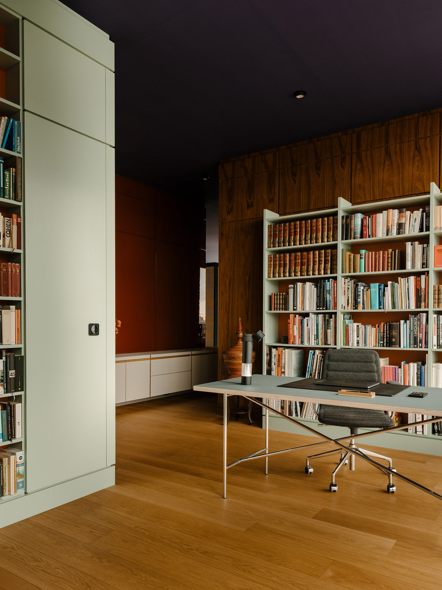 Study with mint green desk and storage and wood-panelled walls inside Berlin apartment designed by Gisbert Pöppler