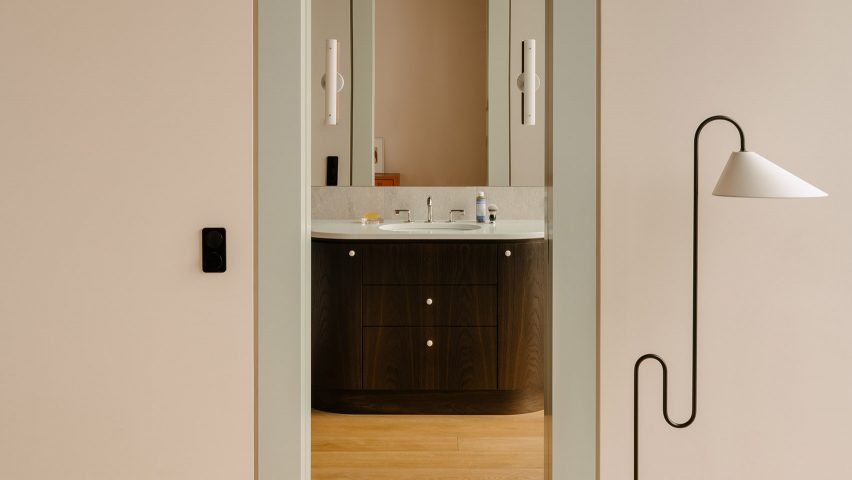 Wavy black floor lap next to entry to guest bathroom with dark wooden vanity inside The Village apartment