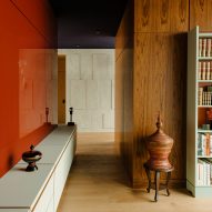 Paredes revestidas de teca, madera lacada en rojo y piedra caliza en el interior del apartamento berlinés The Village diseñado por Gisbert Pöppler