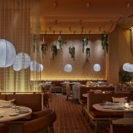 Terracotta-tiled dining room of New York's Casa Dani restaurant designed by Rockwell Group with leather-upholstered seating booths separated by sheer curtains and illuminated by lantern-style lights