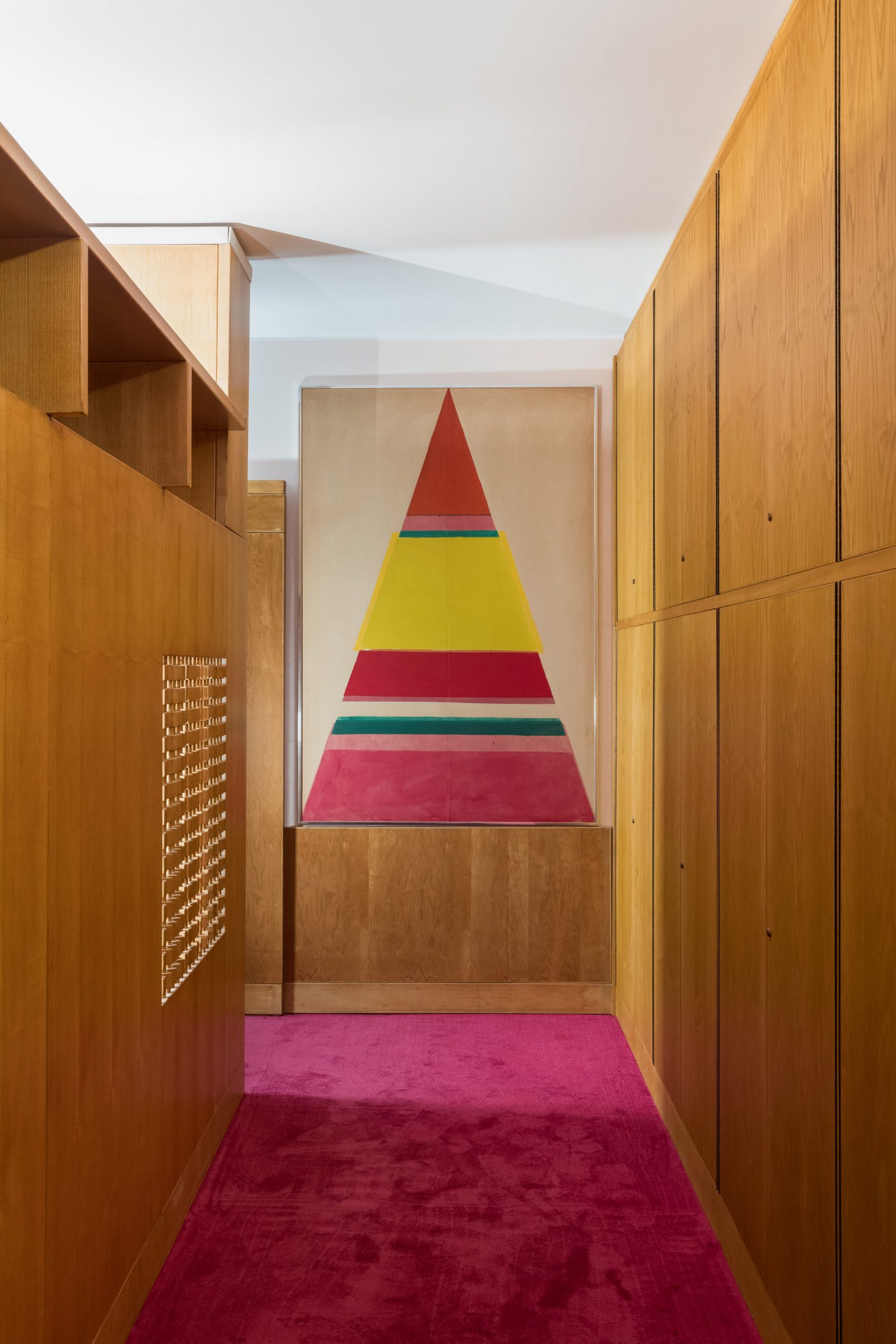 Wood-panelled corridor with magenta carpet and artwork in living room designed by Ettore Sottsass and reconstructed at Triennale di Milano, Italy
