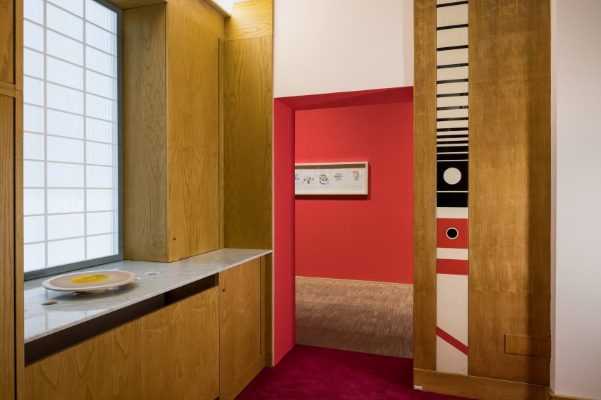 Entrance to Ettore Sottsass installation at Triennale di Milano with built-in wooden storage and marble counter