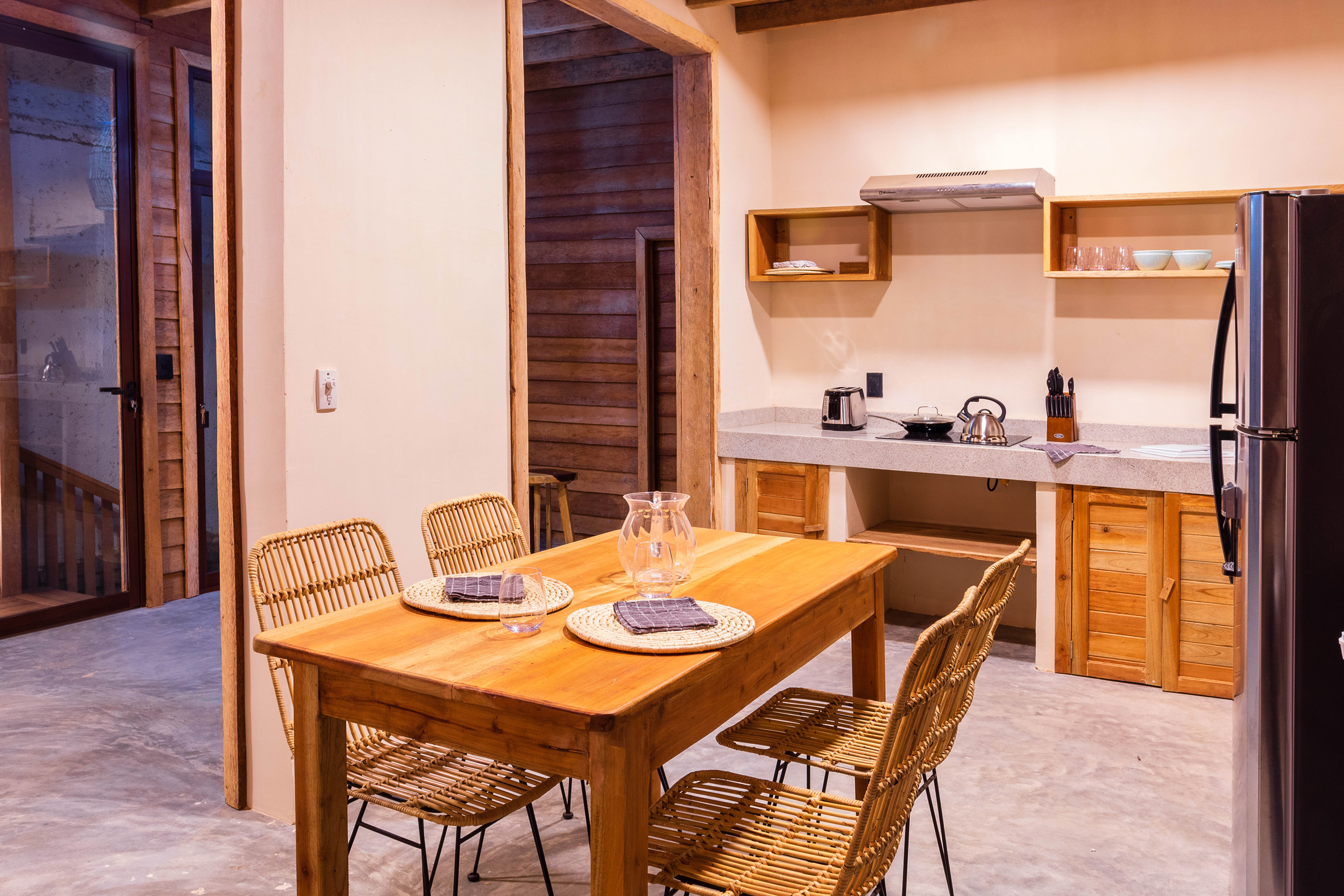 Kitchen finished with chukum and white soil aggregate and furnished with timber dining table