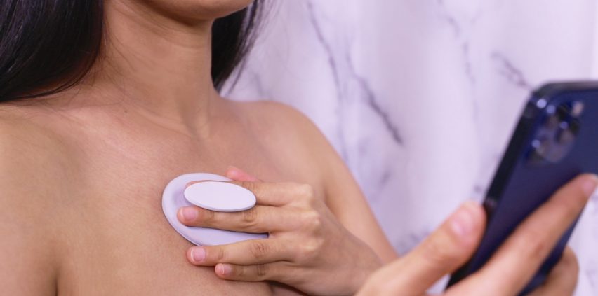 A woman using a pink device on her chest
