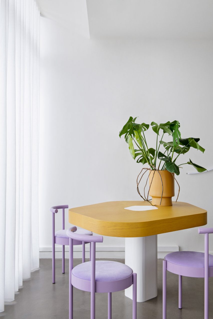 Timber worktable surrounded by four lilac chairs by the window at Mitch salon Melbourne