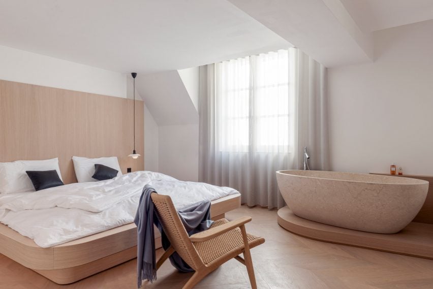 Nicolai Paris bedroom apartment by NOA with a bath on a wooden step and a double bed with white bedding