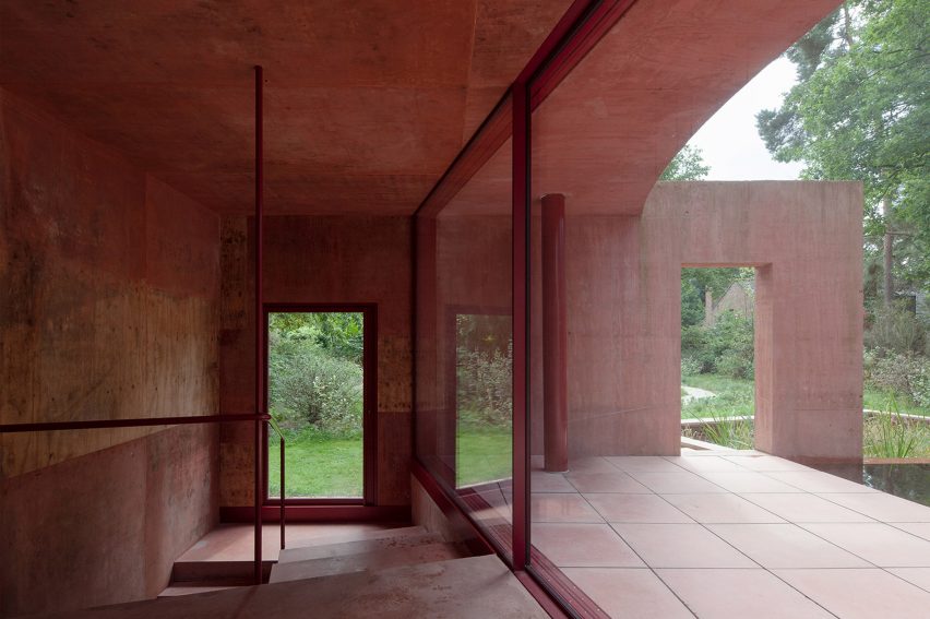 Interior of the Refuge pool house with red stained plywood cladding and large sliding glass door leading to the patio