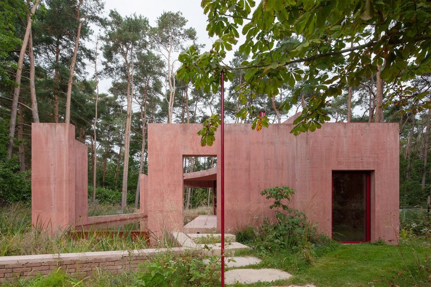 Garden path leading to the entrance of the Refuge pool house with large red concrete walls and pond