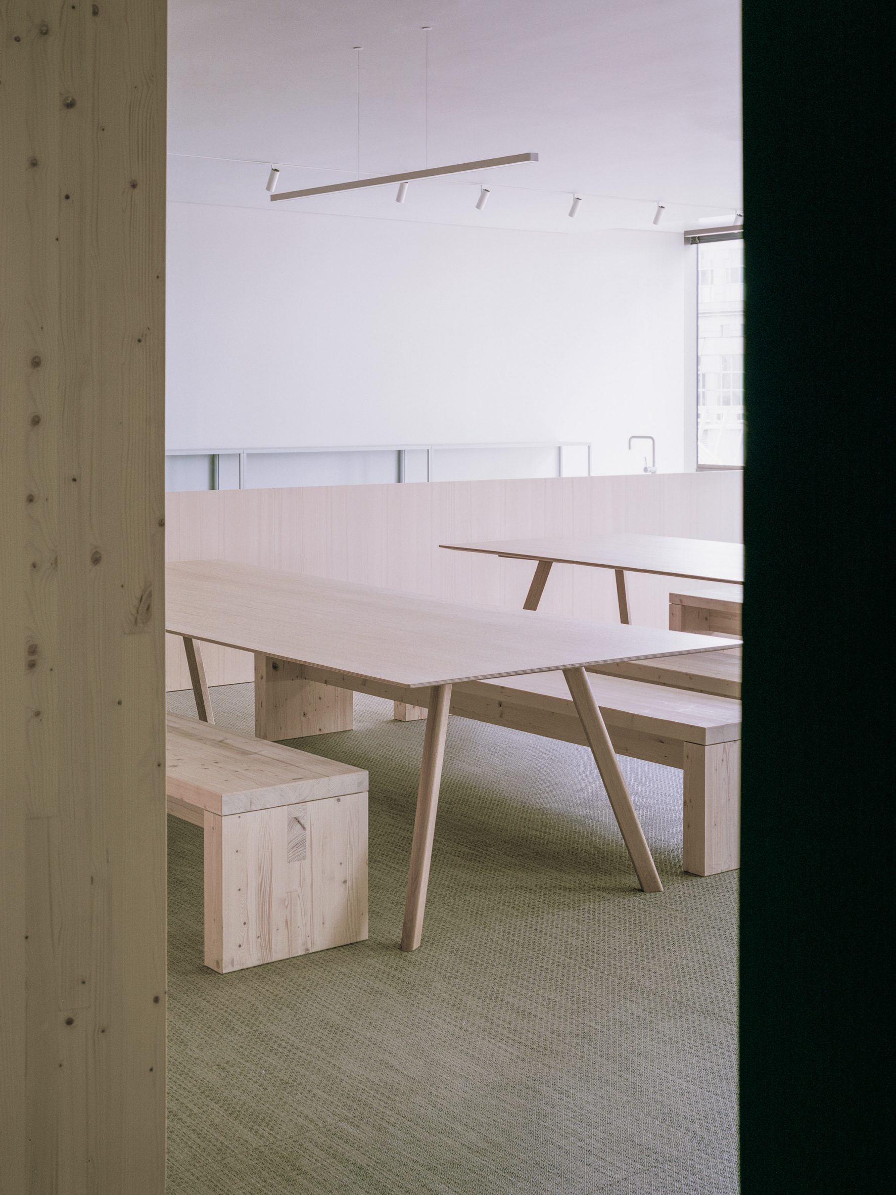 Light wooden tables and benches in breakout area of Samsung Design Europe office