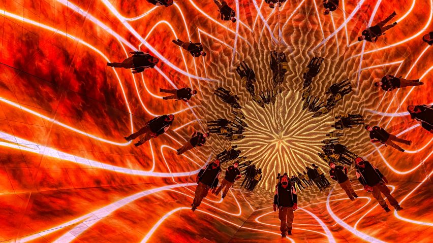 People walk through an immersive digital installation surrounded by red visualisations on all sides