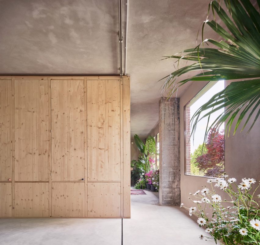 Wooden volume inserted into shell of apartment with plant-filled corridor running along its length 
