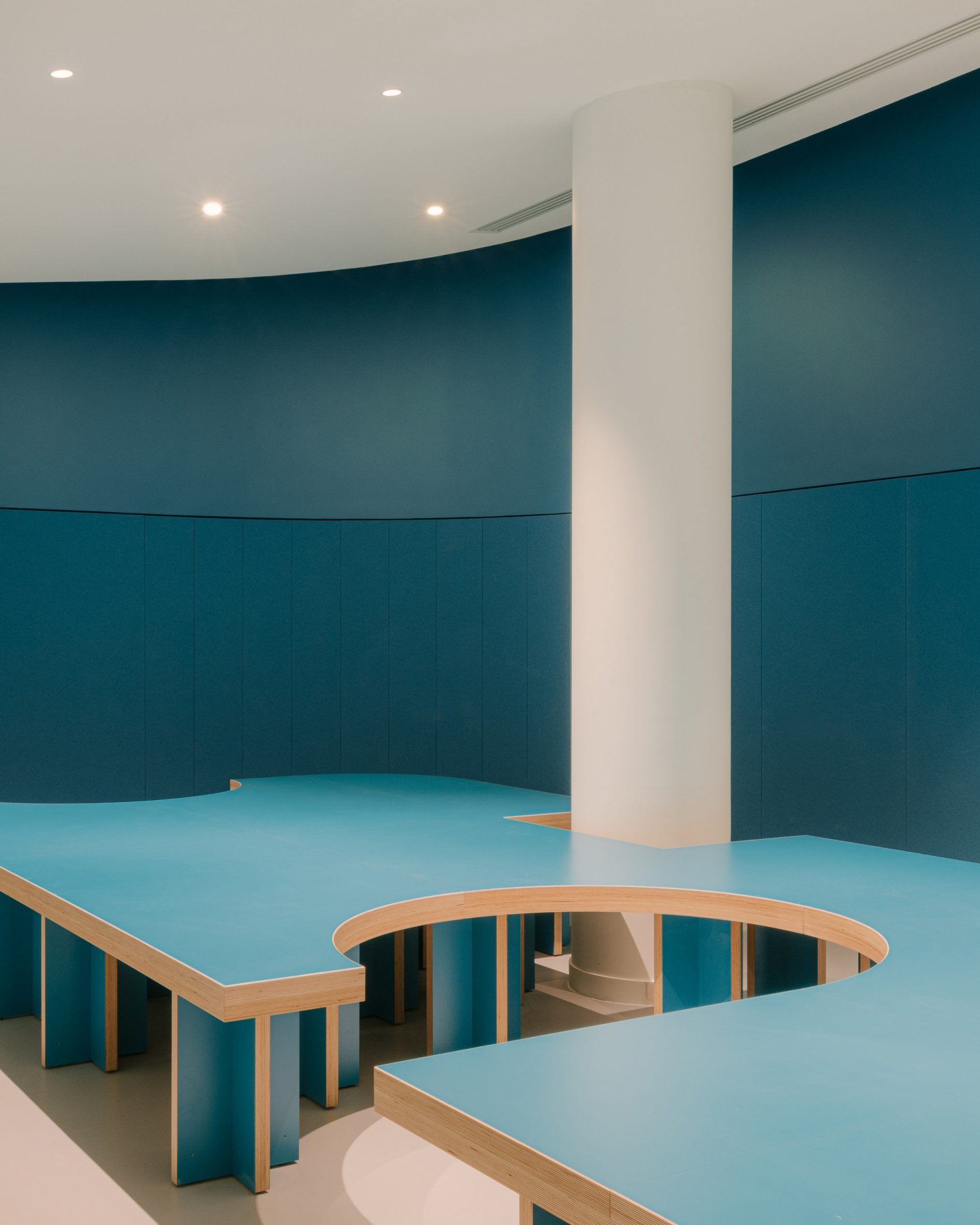 Teal-blue bench seating inside The Studio by h2o Architectes 