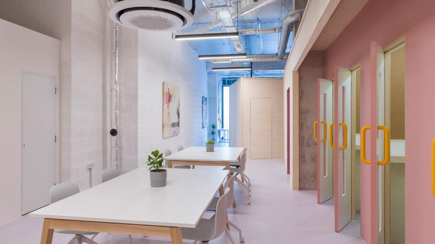 White workbenches in front of baby pink doors in ARC Club Camberwell co-working office by Caro Lundin