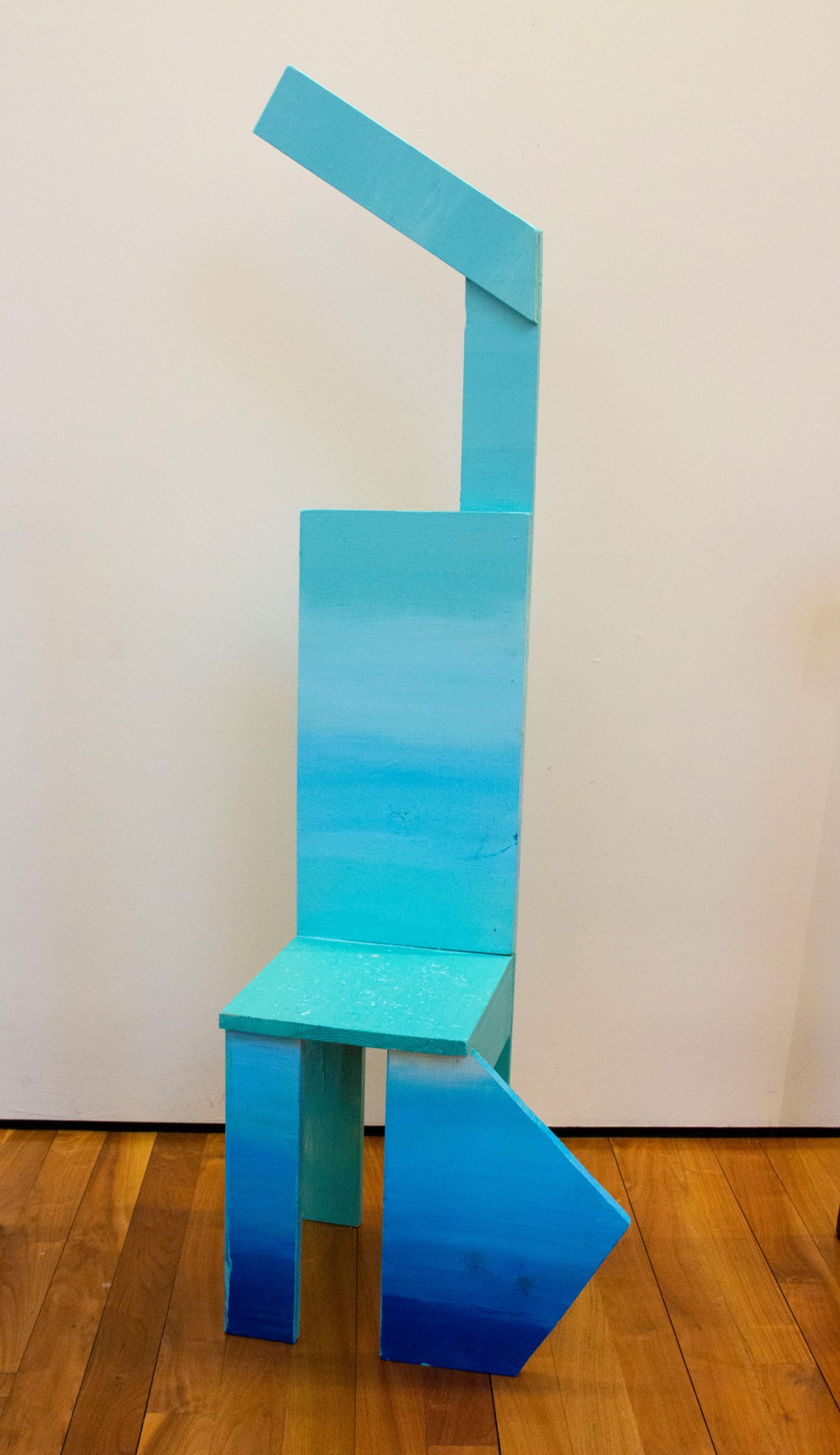 Abstract ballet-inspired chair featuring one arm raised overhead and one triangle leg suggesting a bent leg, all painted ombre blue