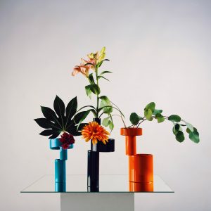 Three colourful vases are filled with flowers