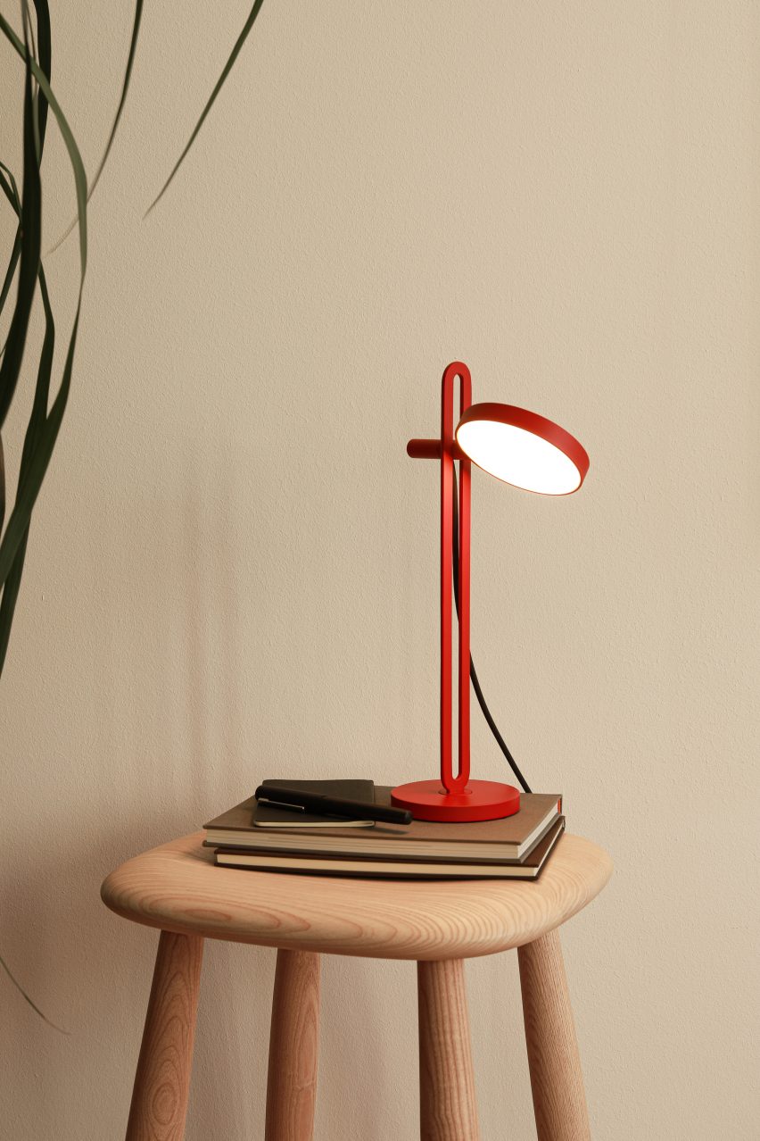 Red Echo lamp by Caussa on a wooden seat with a stack of books
