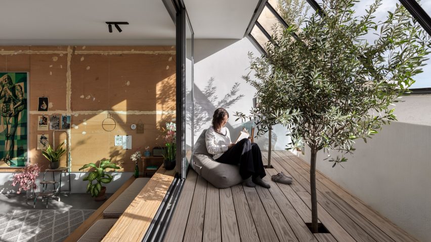 Girl sitting on sun terrace leading down into kitchen of La Serenissima house by Valentino Architects