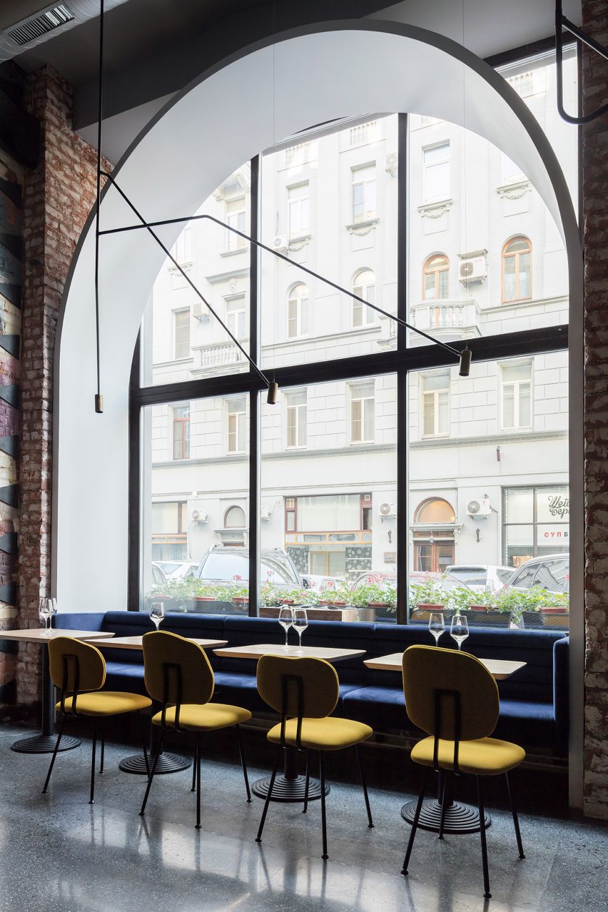 Four yellow Maarten Baas 101 chairs in a restaurant with large arched window