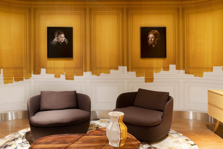 Brown armchairs in front of white and yellow painted wall with Dutch master replicas in airport lounge designed by Marcel Wanders
