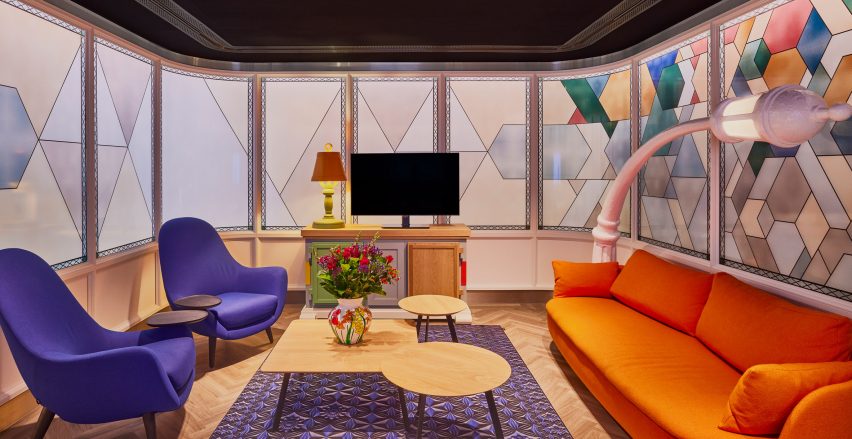 Lounge area of airport lounge designed by Marcel Wanders with orange and purple seating and fake stained glass windows