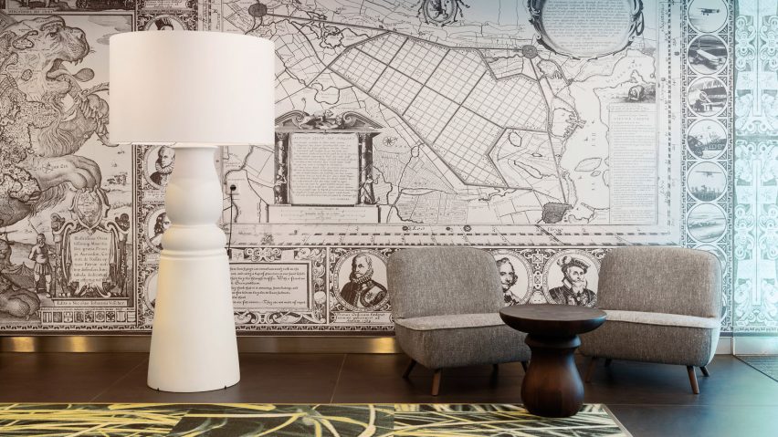 Grey armchairs and tall white floor lamp in front of map wallpaper in VIP centre at Schiphol airport, designed by Marcel Wanders