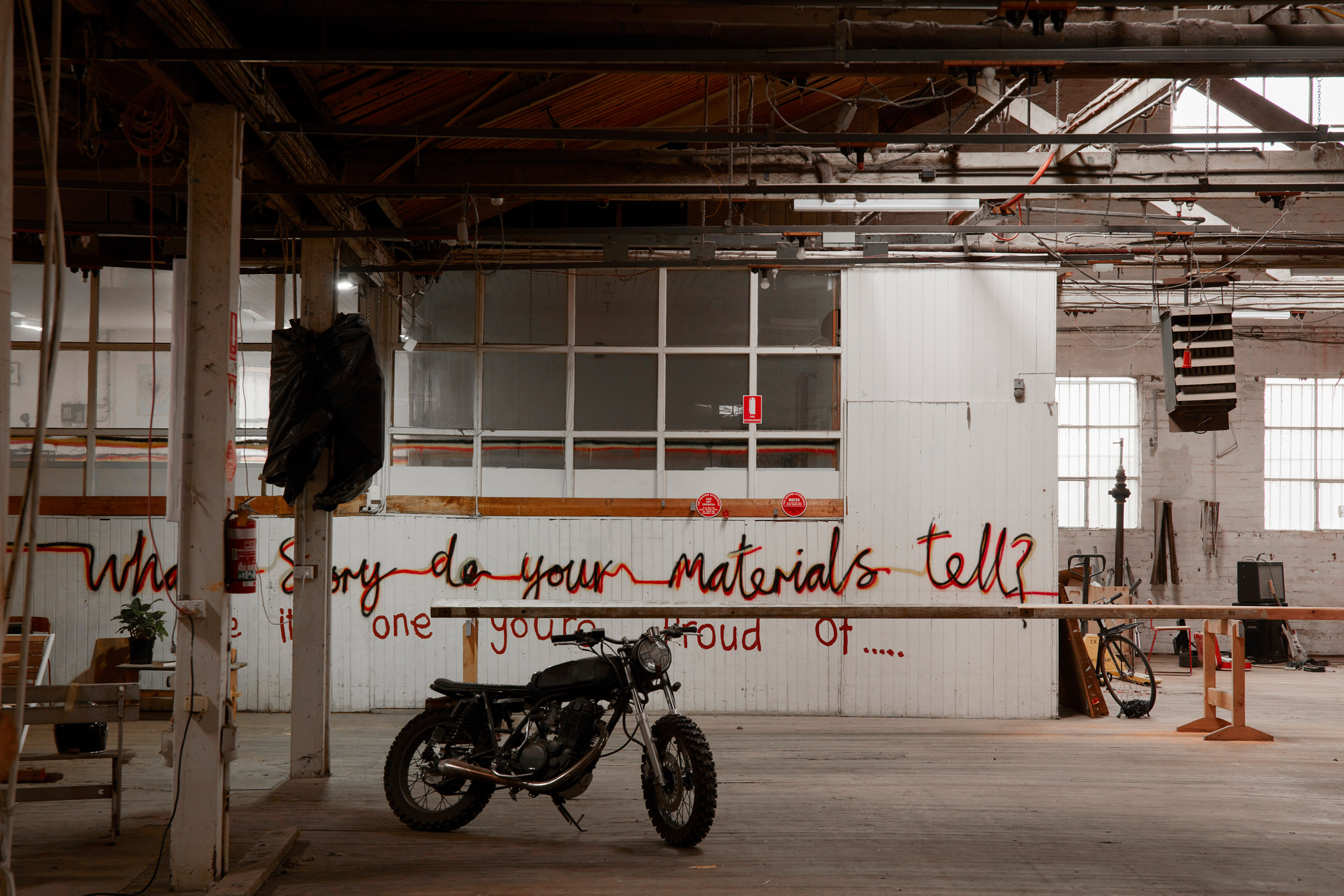 Inside the Zero Footprint Repurposing Hub warehouse where 'what story do your materials tell?' has been spray-painted on one wall