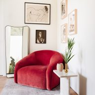 red plush sitting chair with mirror and art