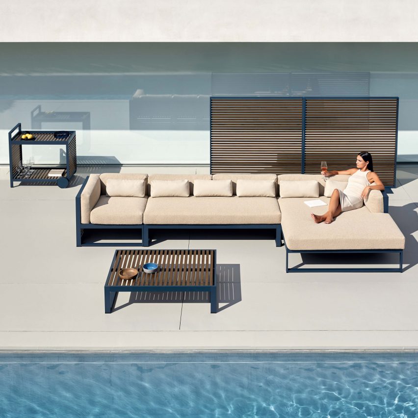 Blue grey serving cart, coffee table, sofa and partition on an indoor pool setting.