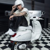 Justin Bieber in a white helmet sitting on a scooter he designed for Vespa