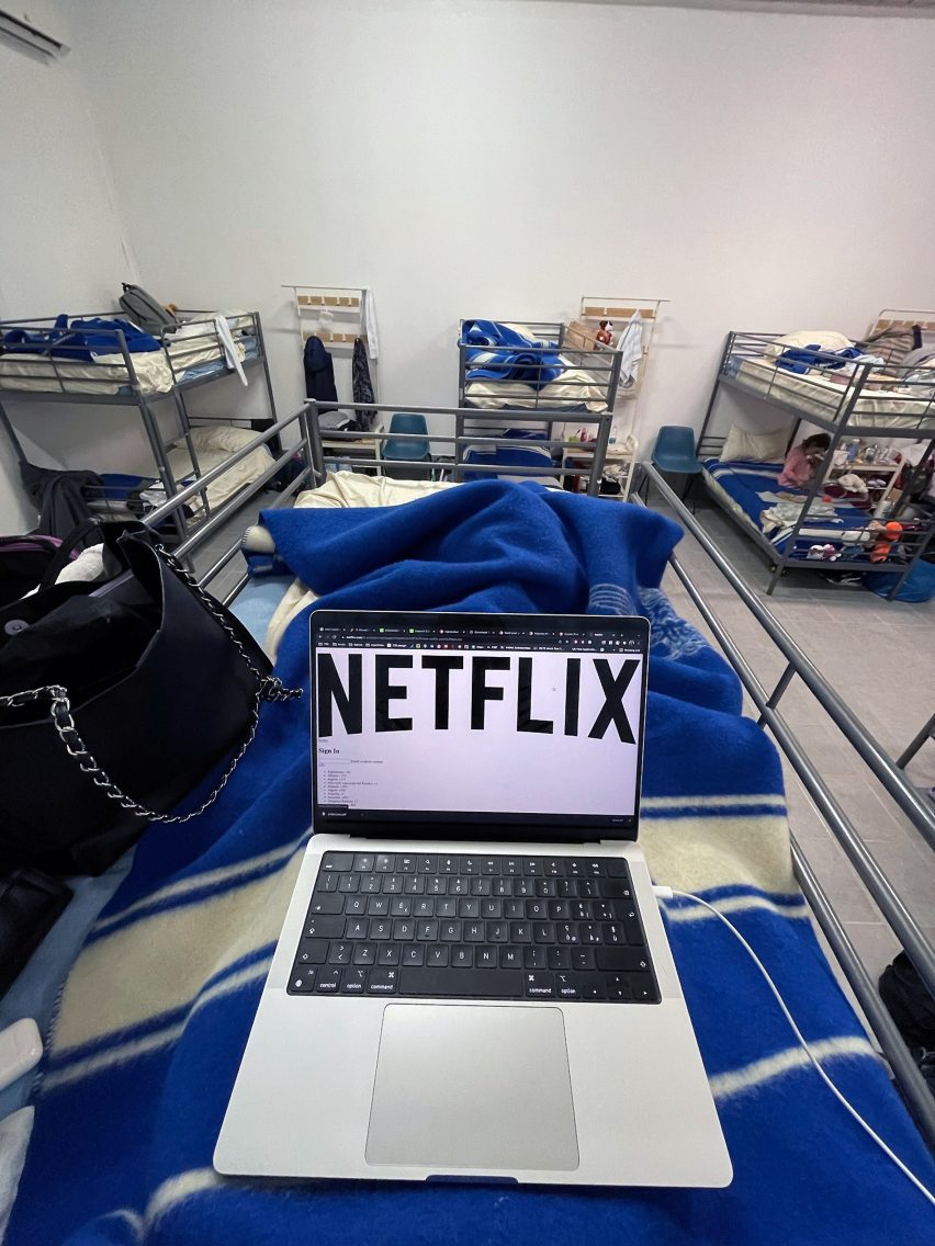 Photo of a laptop with the Netflix website up as photographed from the top of a bunk bed in camp for refugees of Ukraine war