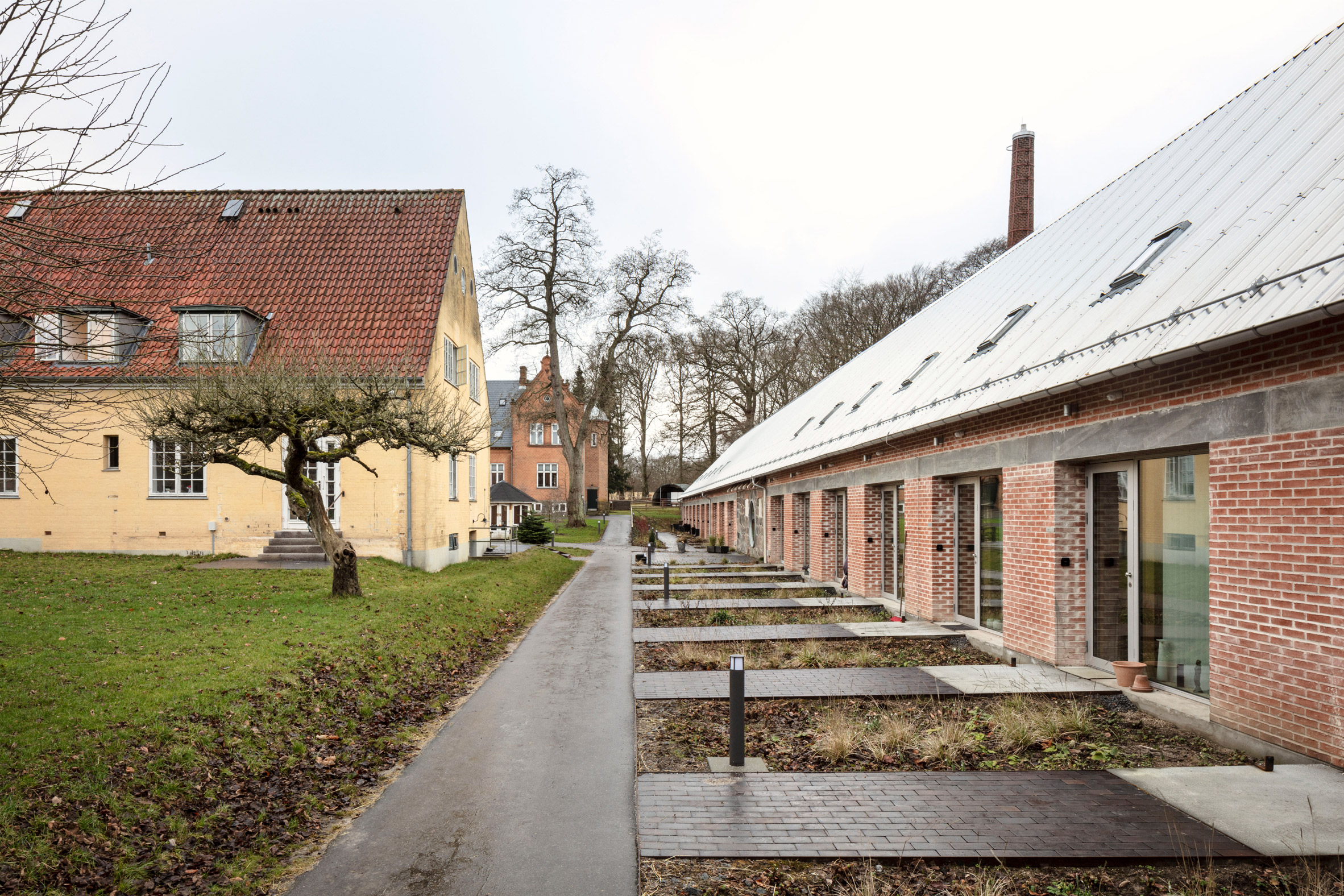 Paved walkways lead up to glazed doors at Supportive housing in Stubberupgård 