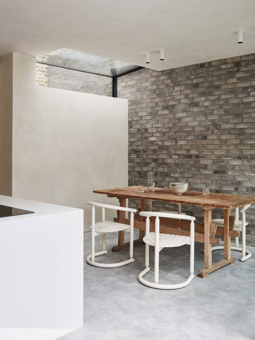 Dining room of Reighton Road house with brick wall and timber table