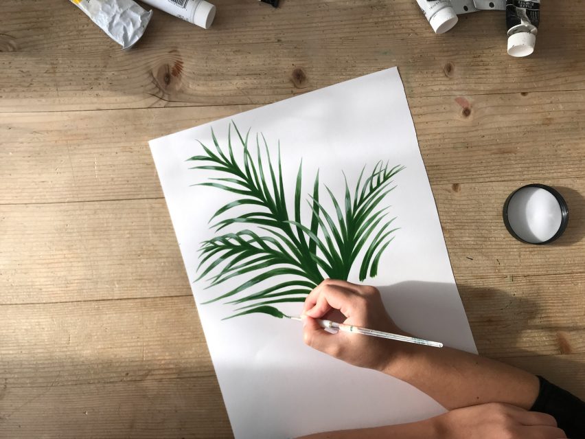 Flatlay of an artist's worktable with hand painting plant leaves on white paper