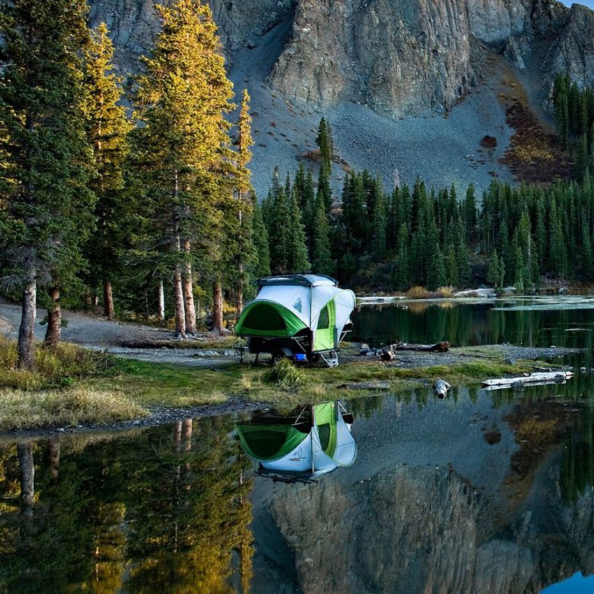 SylvanSport Go camping trailer parked by an isolated lake surrounded by mountains