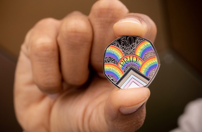 A person of colour holding a Pride 50p coin