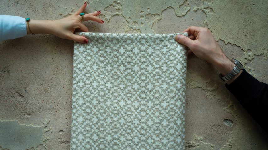 Hands holding up a sheet of patterned fabric