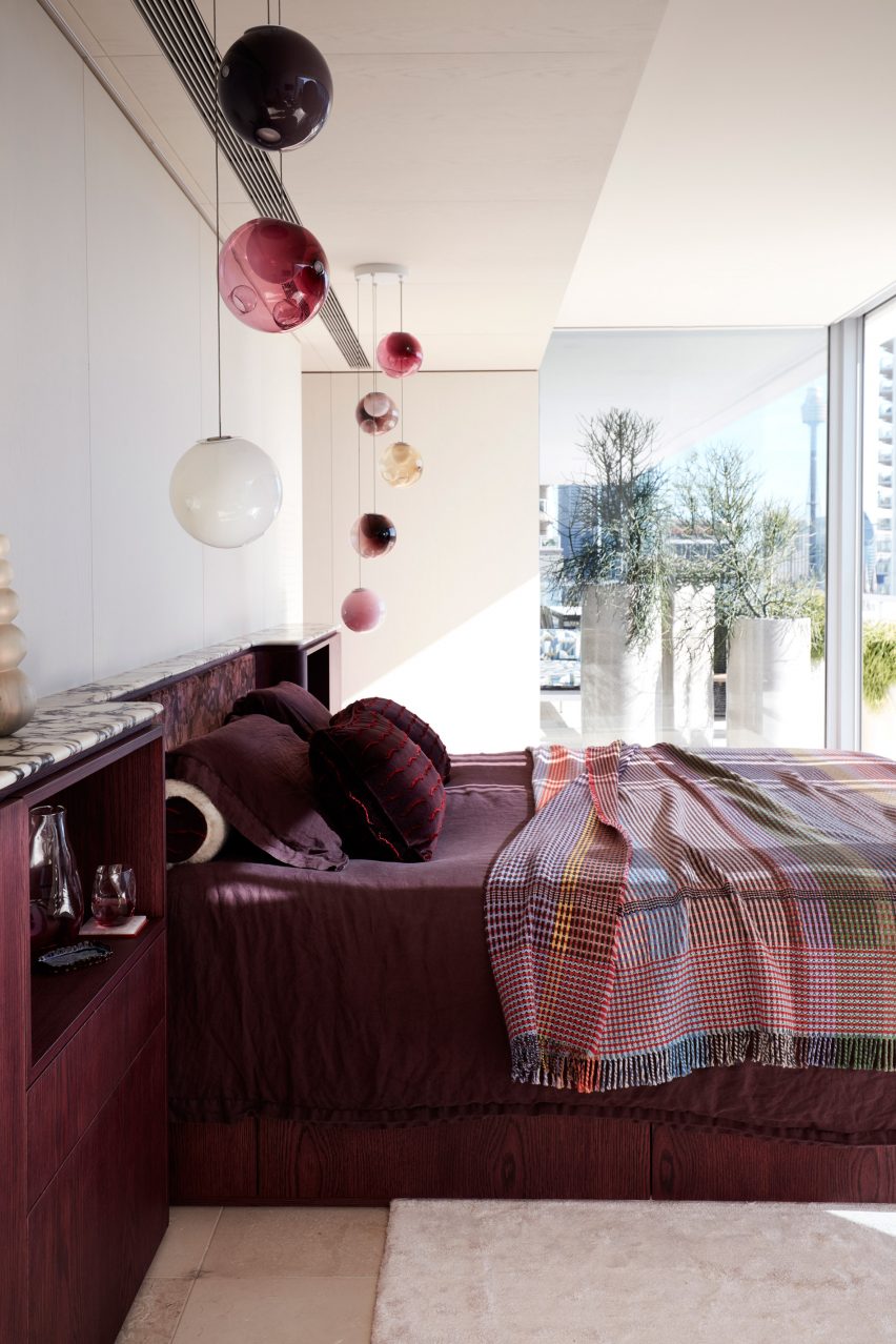Bedroom interior of apartment designed by YSG with berry red bed and pendant lights