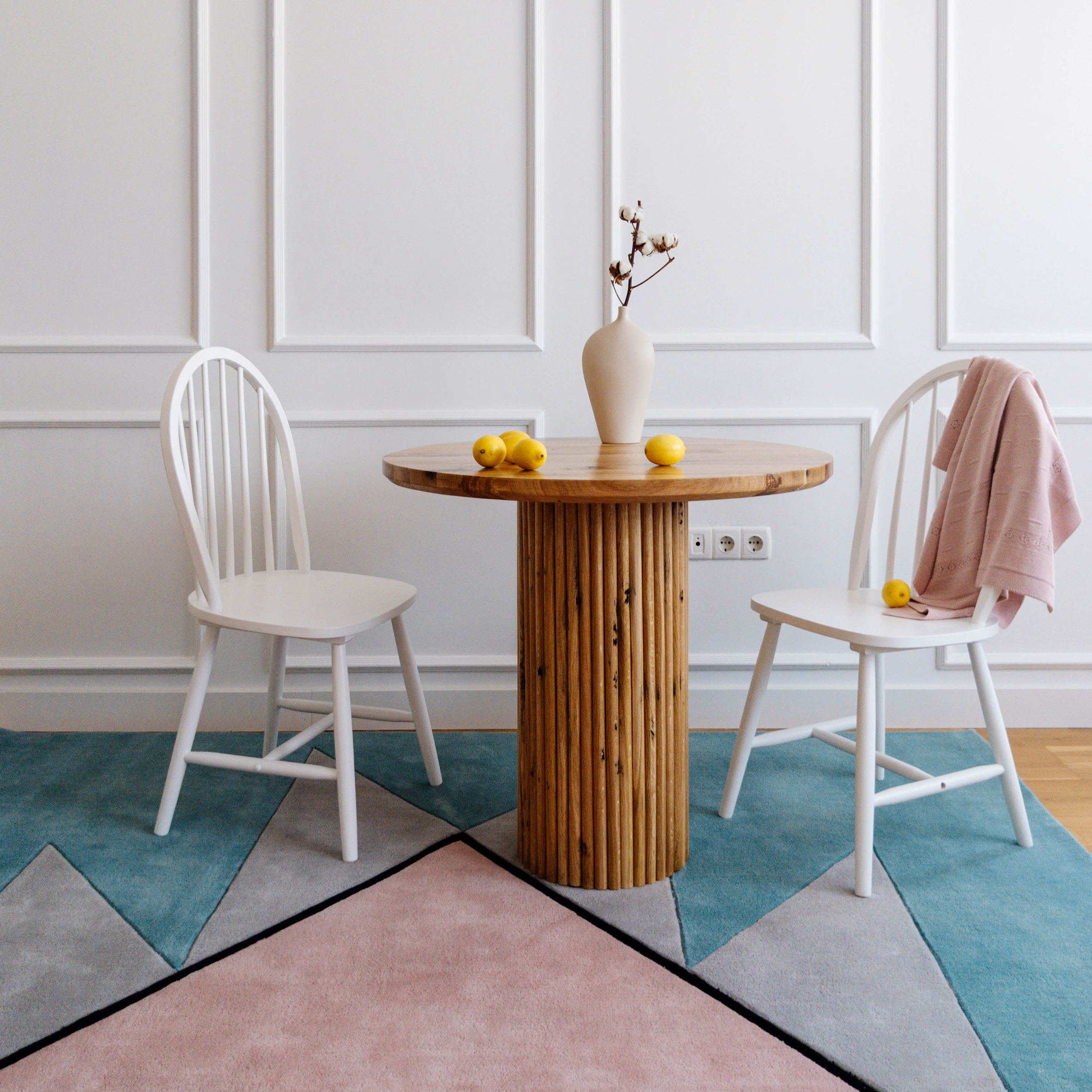 Blue and pink Harmony rug with two white chairs and a side table 