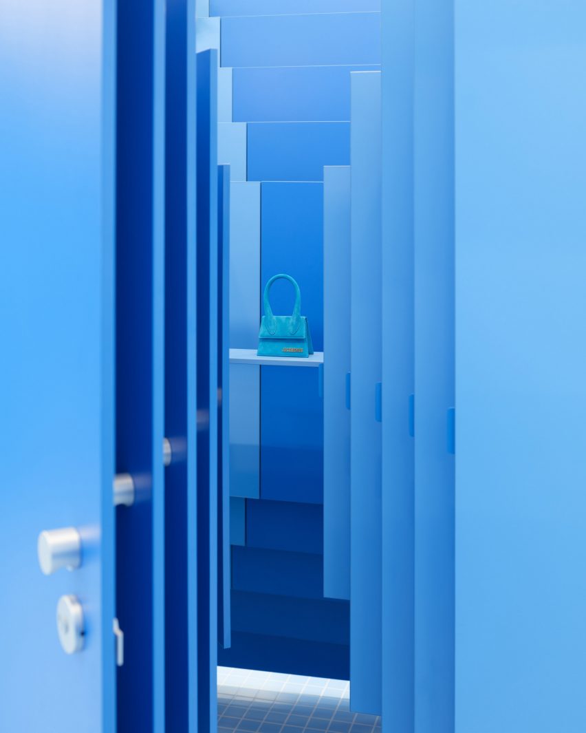 Сумка Jacquemus изображена за сужающимися синими дверцами кабинки.