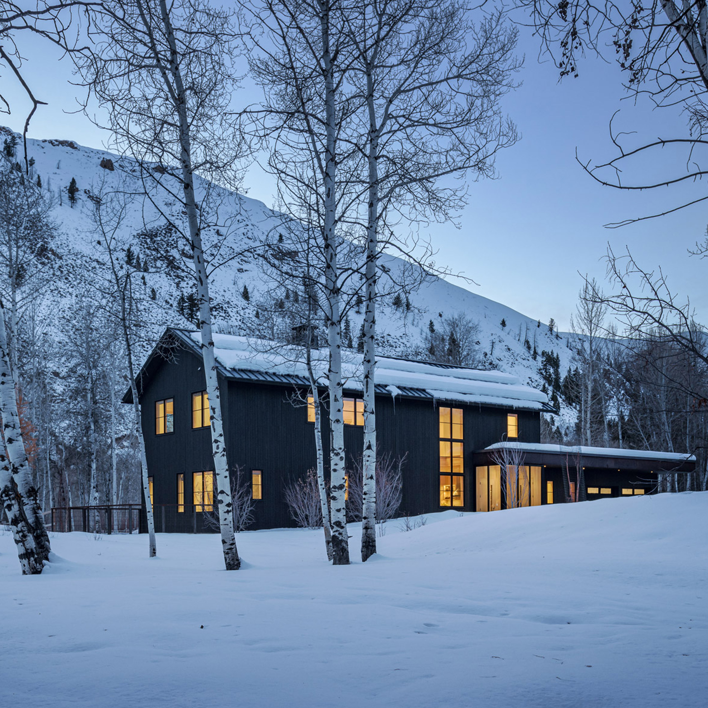 Casa granero vestida de negro en las montañas nevadas